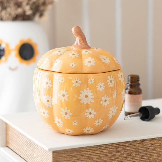 Yellow pumpkin-shaped container with white floral patterns on a surface.