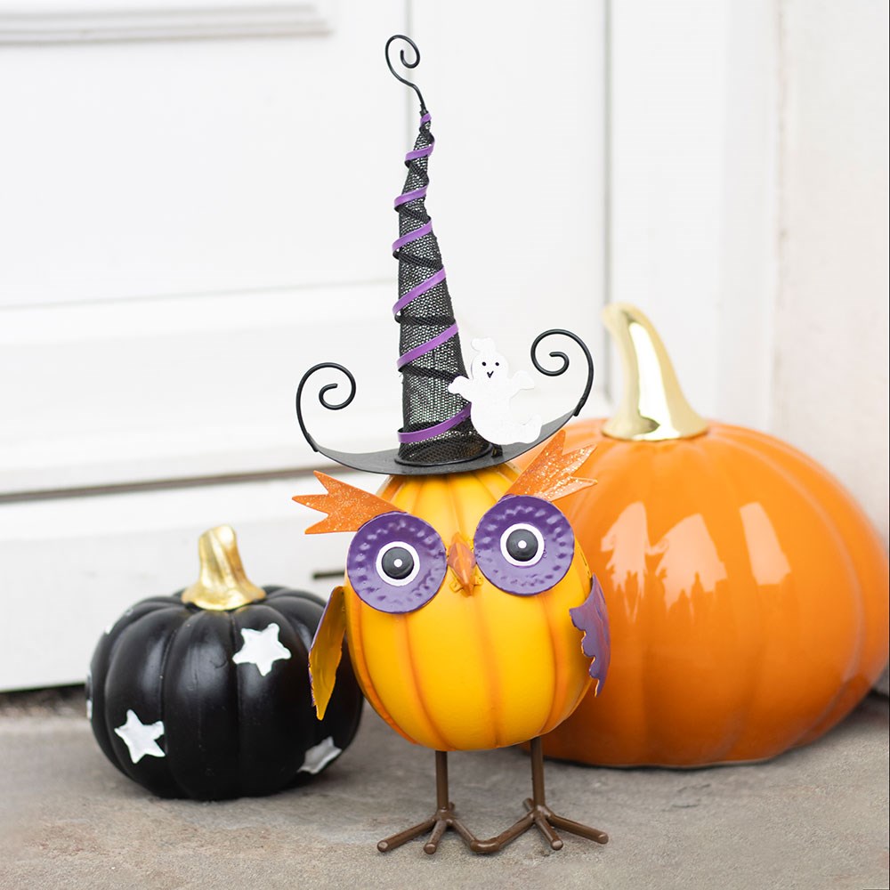Decorative pumpkins with witch hat, owl face, and star decorations on a neutral background