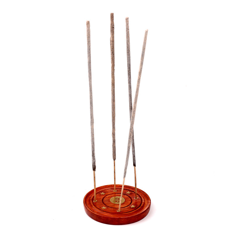 Incense sticks on a wooden stand with decorative patterns on a white background