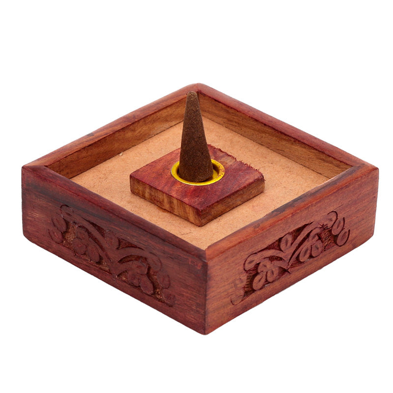 Wooden incense cone holder with intricate carvings on a white background