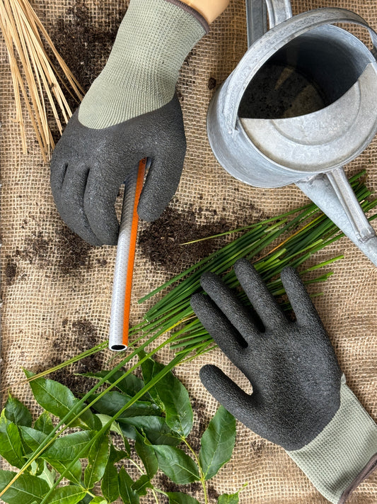 Gardening scene with hands wearing gloves, a watering can, and plants on a textured surface.