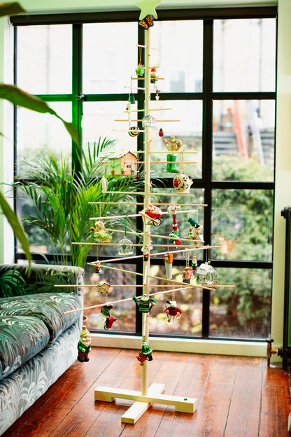 Decorative Christmas tree with ornaments in a room with large windows.