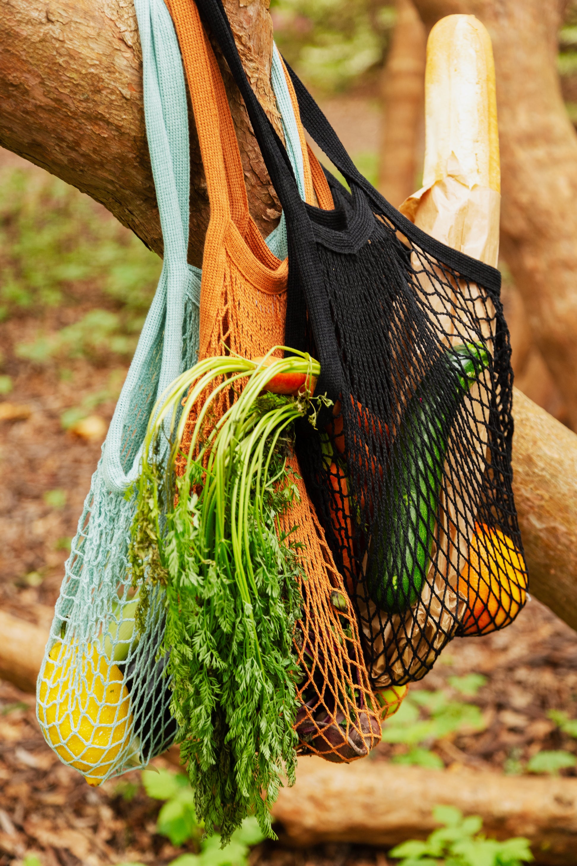 Black string shopping bag filled with bread and carrots in an outside setting
