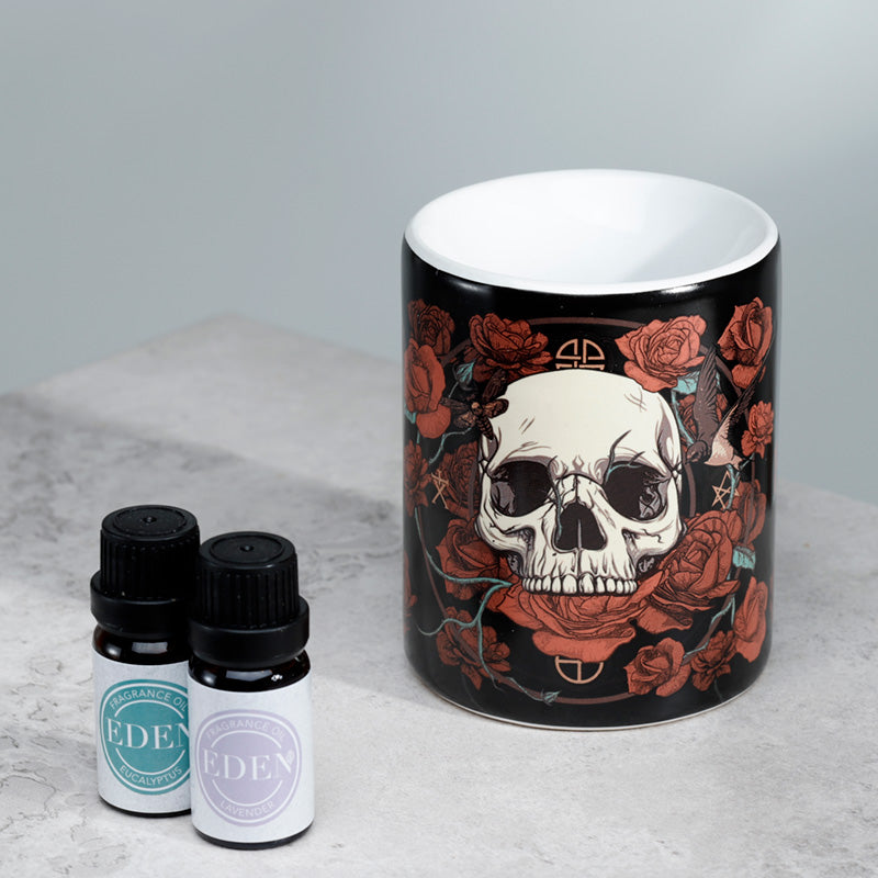 Mug with skull and roses design next to two small bottles on a light gray surface.