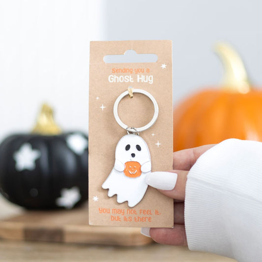 Ghost-shaped keychain on a cardboard backing with pumpkins in the background