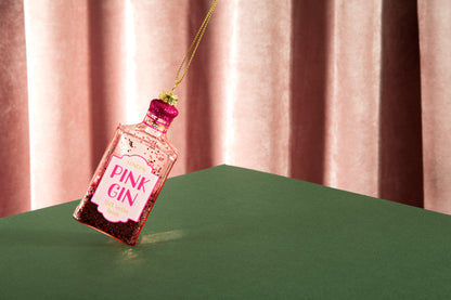 Pink Gin bottle ornament on a green surface with a striped background