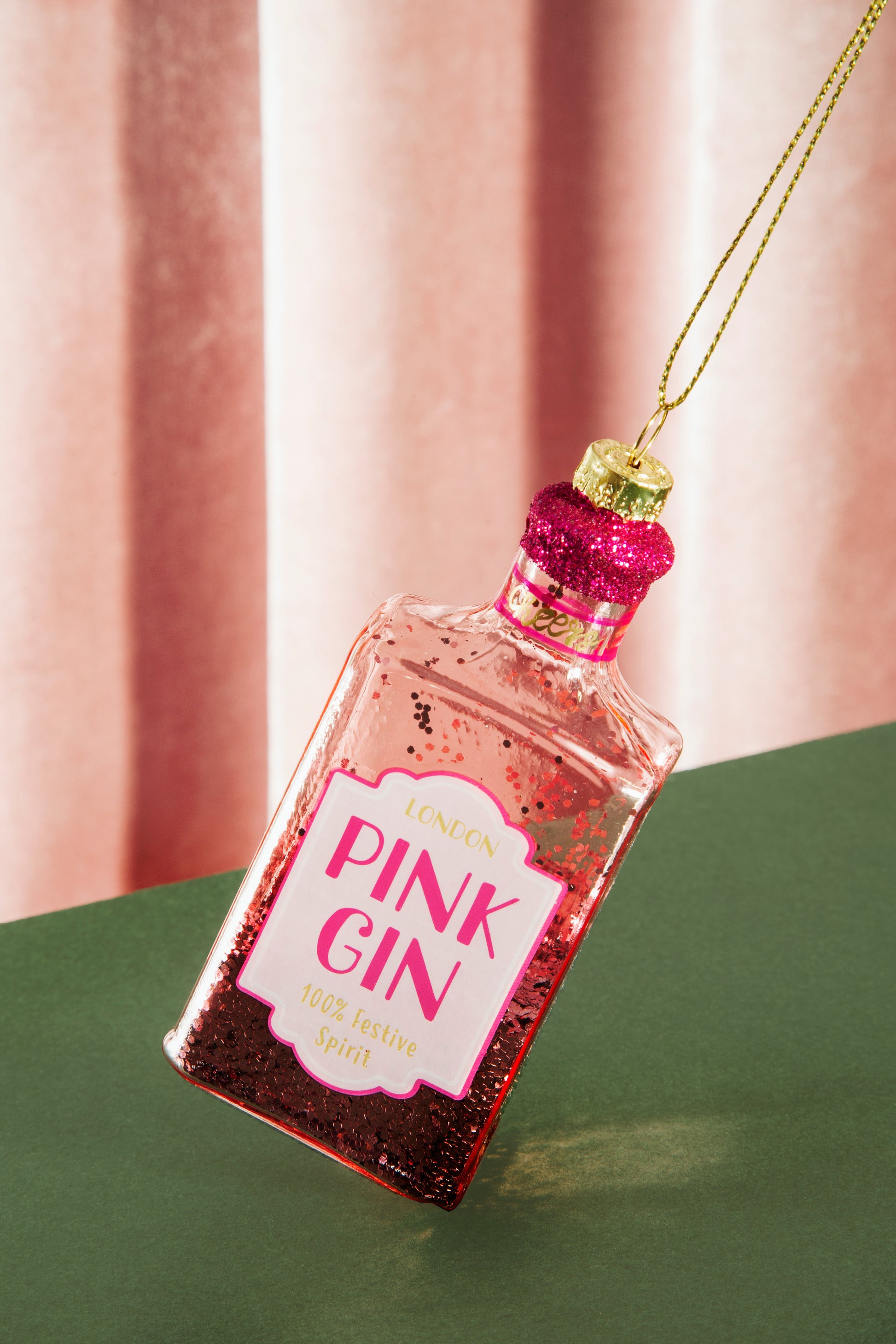 Pink Gin bottle ornament with a pink label against a pink curtain background