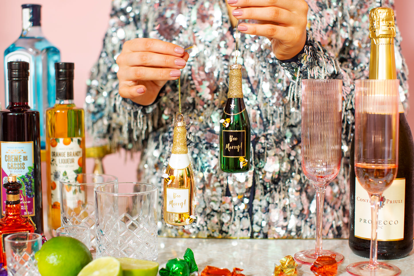 Person preparing a cocktail with various bottles and glasses on a table.