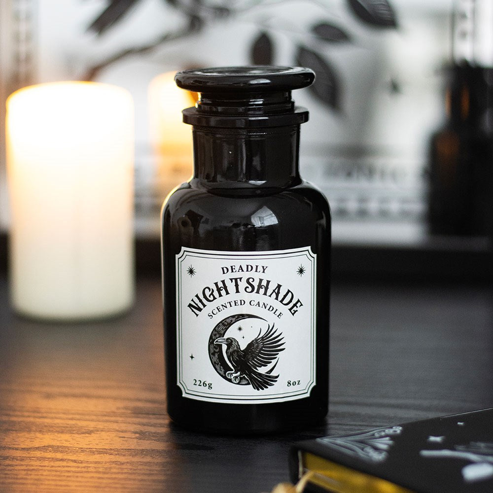 Black candle jar labeled 'Deadly Nightshade' with a candle and book in the background