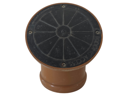 A circular black metal access cover with a brown plastic base, isolated on a white background.