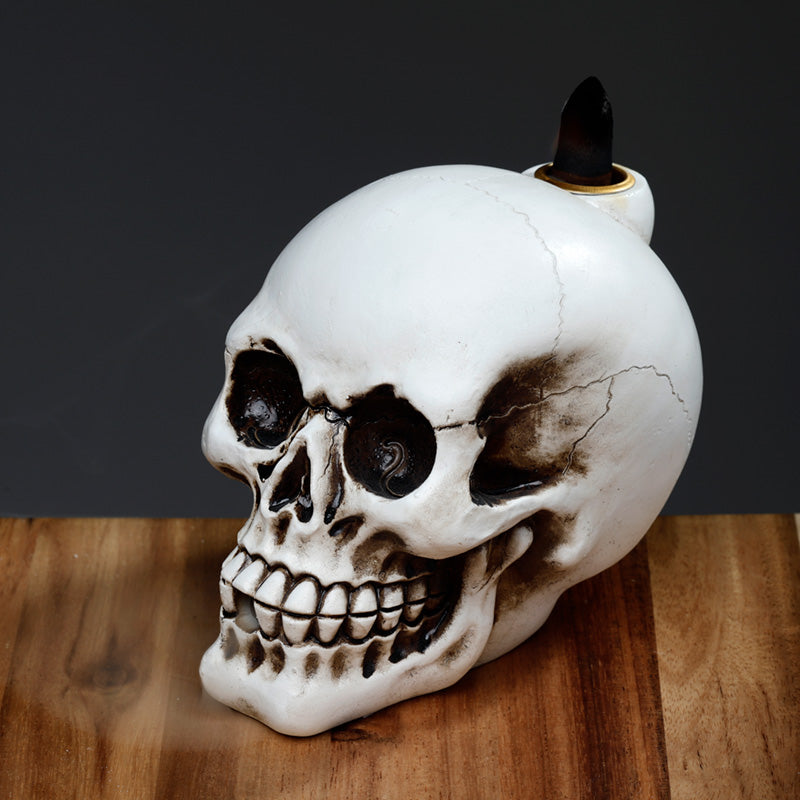 Skull-shaped candle holder with a candle on a wooden surface