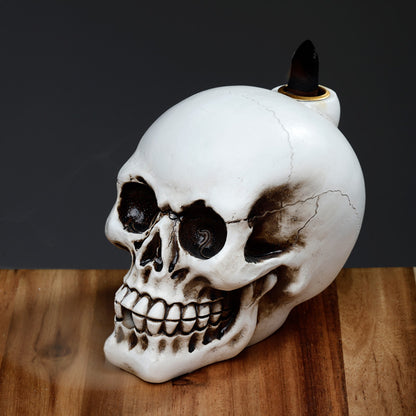 Skull-shaped candle holder with a candle on a wooden surface