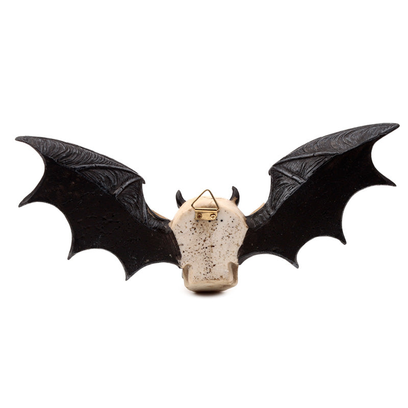 Wall plaque in the shape of a devil's skull with bat wings on a white background