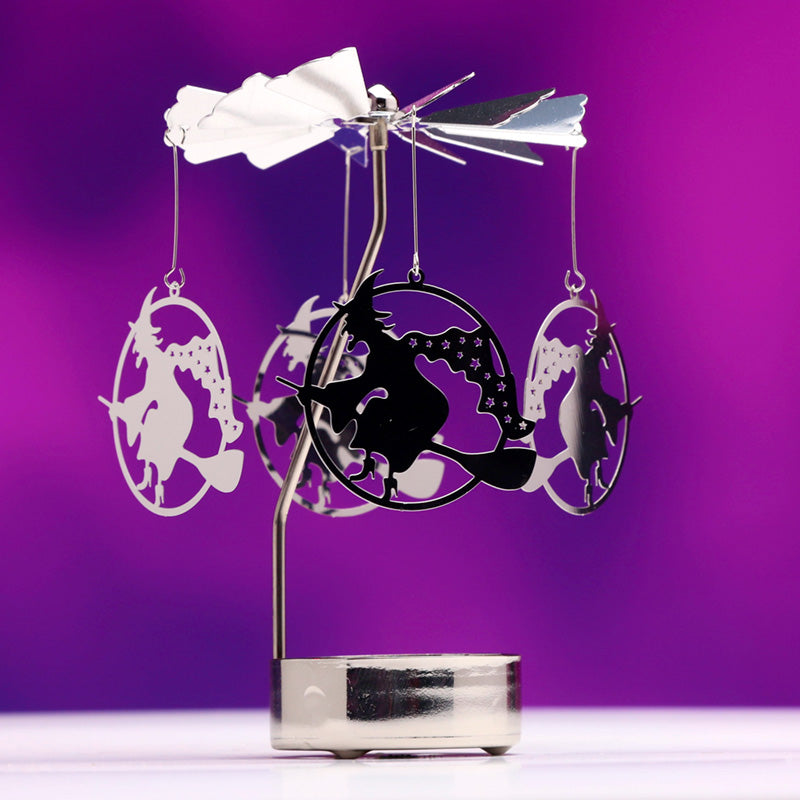 Decorative metal sculpture with silhouettes of a witch, moon, and stars on a purple background