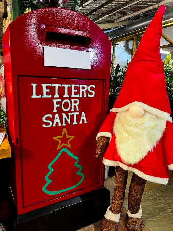Red mailbox with 'Letters for Santa' text and a Christmas tree design, next to a gnome figurine.