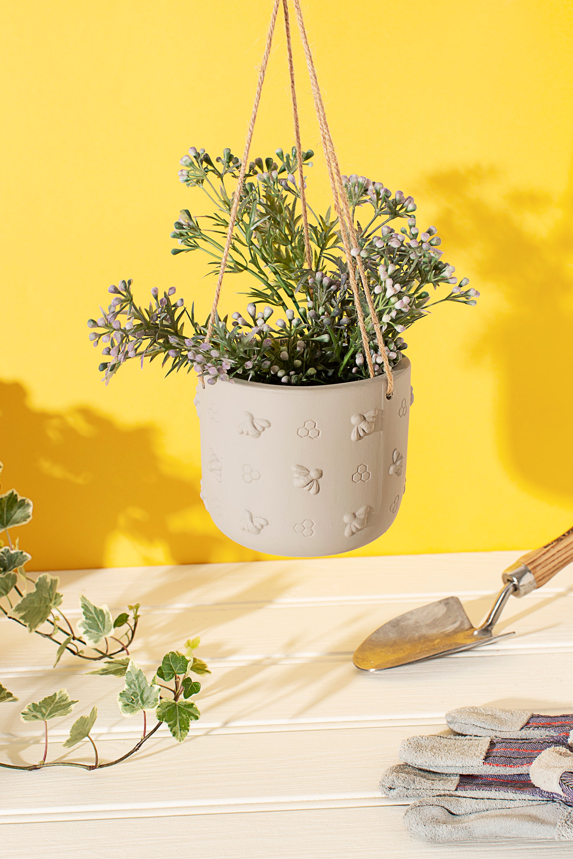 Hanging planter with a plant inside, on a yellow background