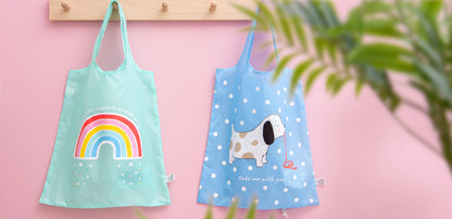 Two shopping bags on a pink background, one with a rainbow design and the other with a dog illustration.