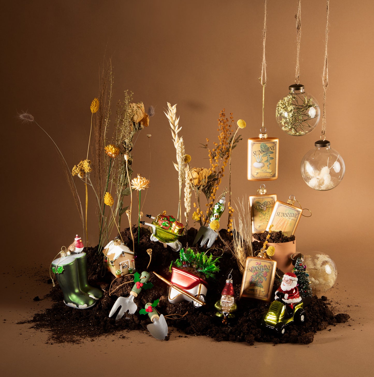 Decorative arrangement with small gardening-themed figurines, plants, and ornaments on a brown background.