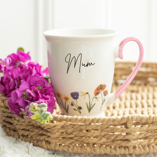 Mug with floral design and pink handle on a woven tray with flowers