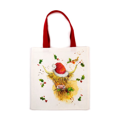 Tote bag with a highland cow wearing a Santa hat and holly leaves on a white background