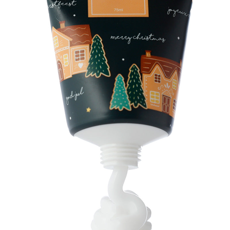 Hand cream with Christmas-themed packaging featuring houses and trees on a white background