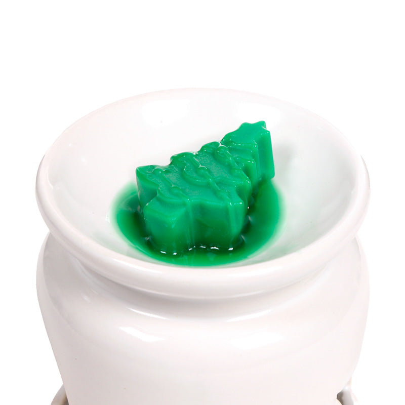 Christmas themed wax melt in a burner on a white background