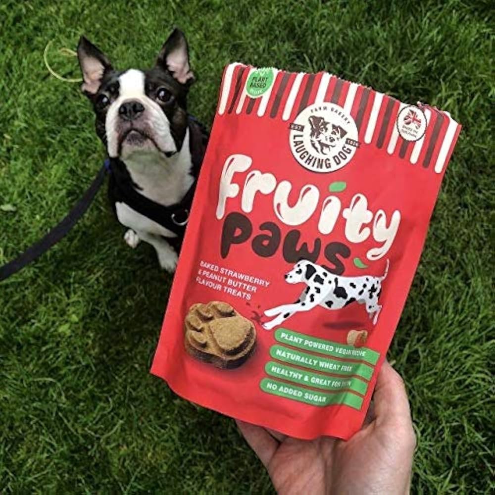 Laughing Dog Fruity Paws Dog Treats (Peanut Butter & Strawberry) 125g on grass next to a brown dog