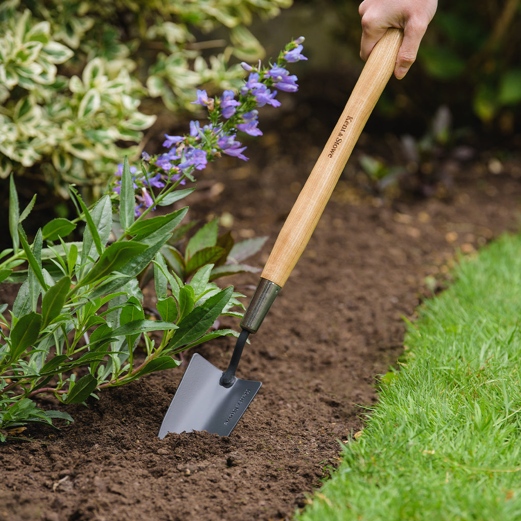 Kent & Stowe Carbon Steel Border Hand Trowel digging soil in a garden bed