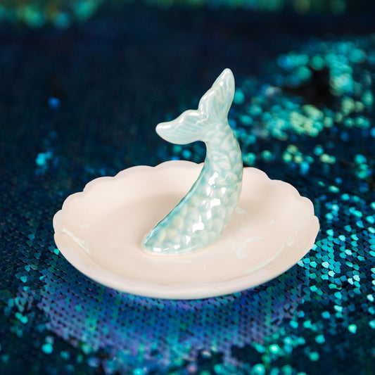 Mermaid tail ring holder on a shell with a glittery blue background