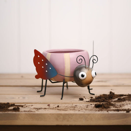 Colorful ladybug-shaped planter on a wooden surface with soil.