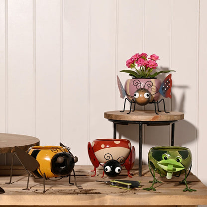 Set of colorful insect-shaped planters on a wooden surface with a white paneled wall background.