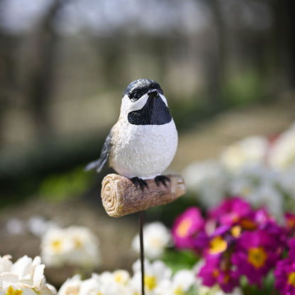 Decorative bird on a stick with flowers in the background