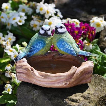 Decorative bird figurine on a natural base with flowers in the background