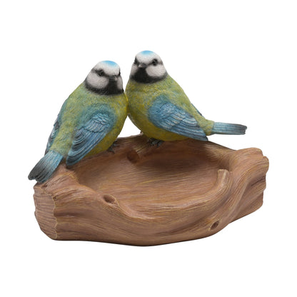 Two bird figurines perched on a wooden branch on a white background