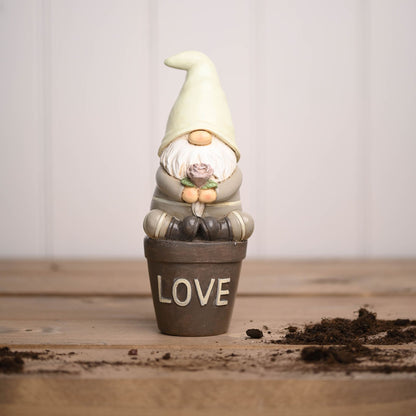 Gnome figurine in a pot labeled 'LOVE' on a wooden surface
