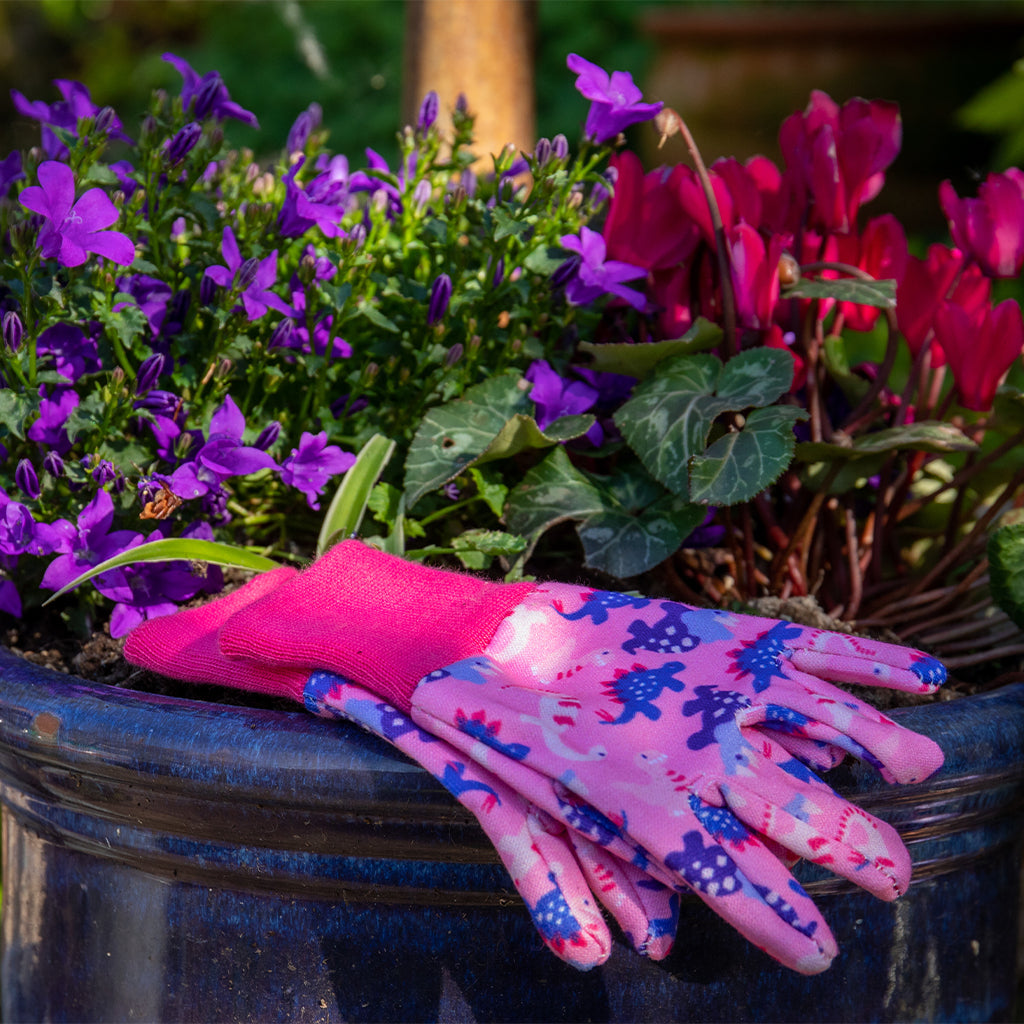 Pink gardening gloves with blue patterns on a pot of purple flowers