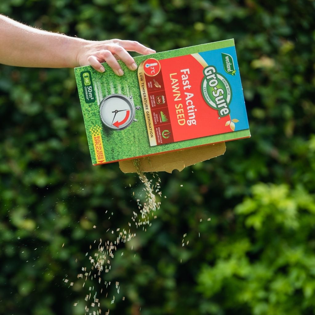 Person pouring Gro-Sure Fast Acting Lawn Seed into a garden bed with greenery in the background