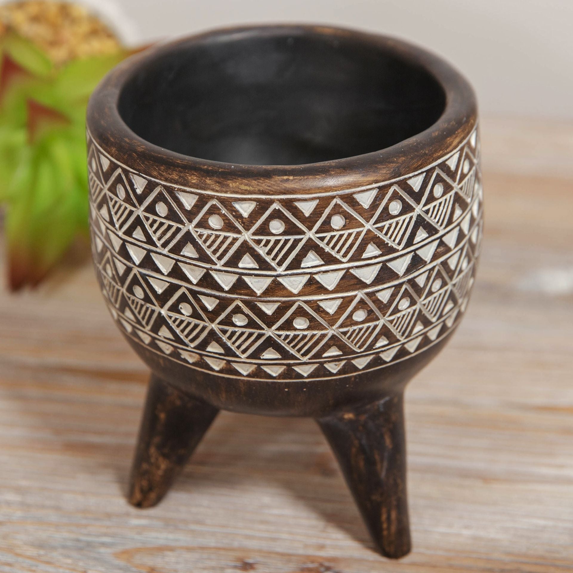 Ceramic pot with tribal patterns on a wooden surface