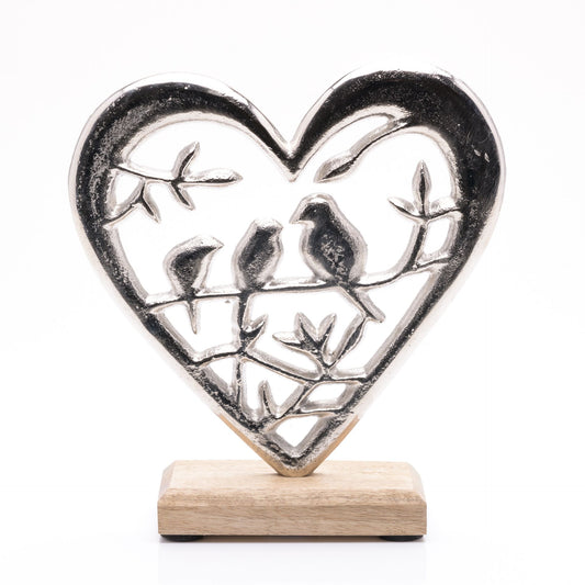 Decorative heart-shaped metal sculpture with birds on a wooden base against a white background