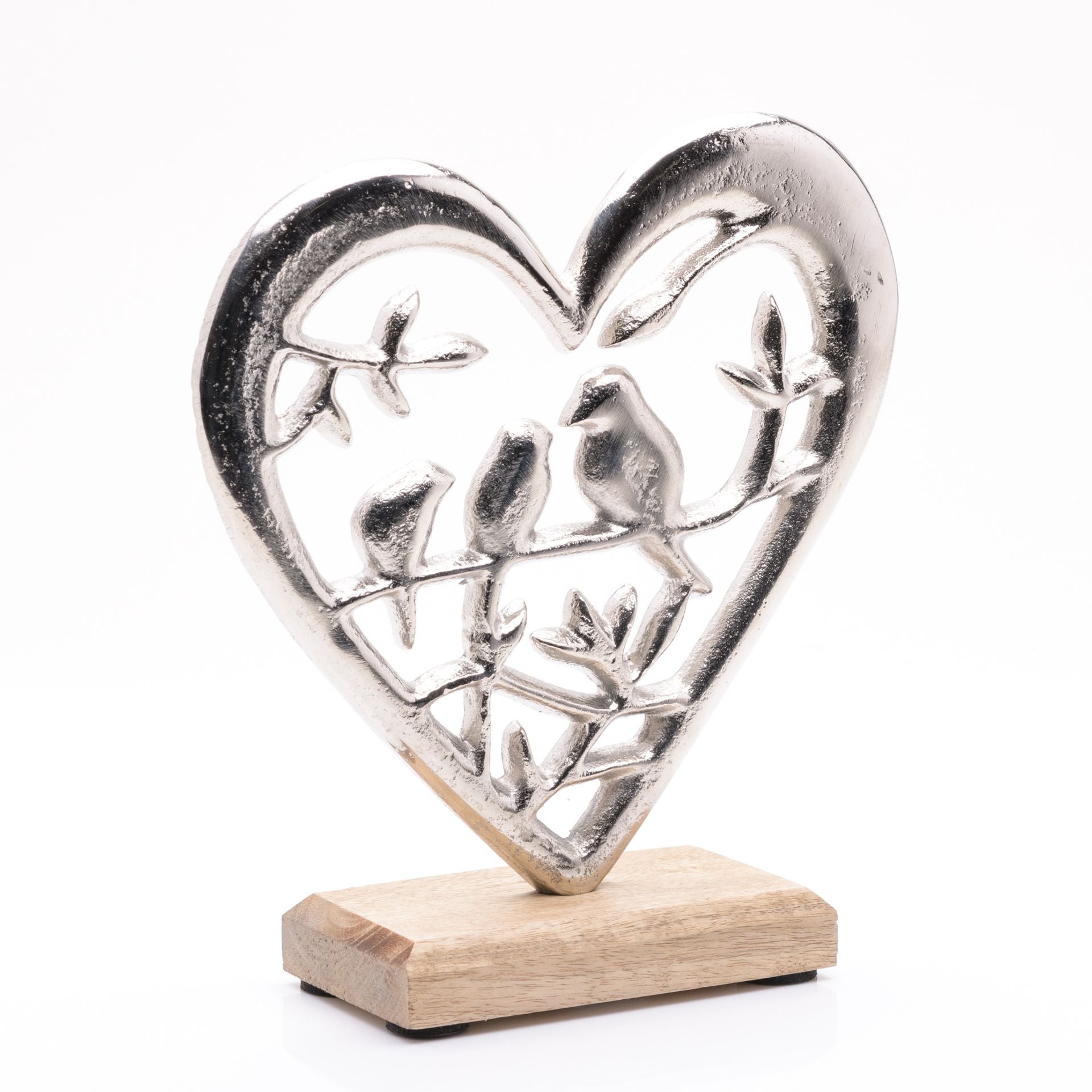 Silver heart-shaped sculpture with cut-out figures on a wooden base against a white background