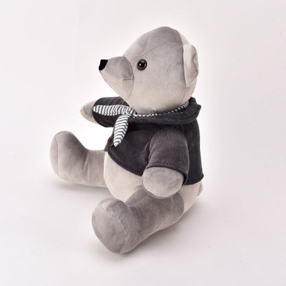 Gray teddy bear wearing a black sweater and striped scarf on a white background