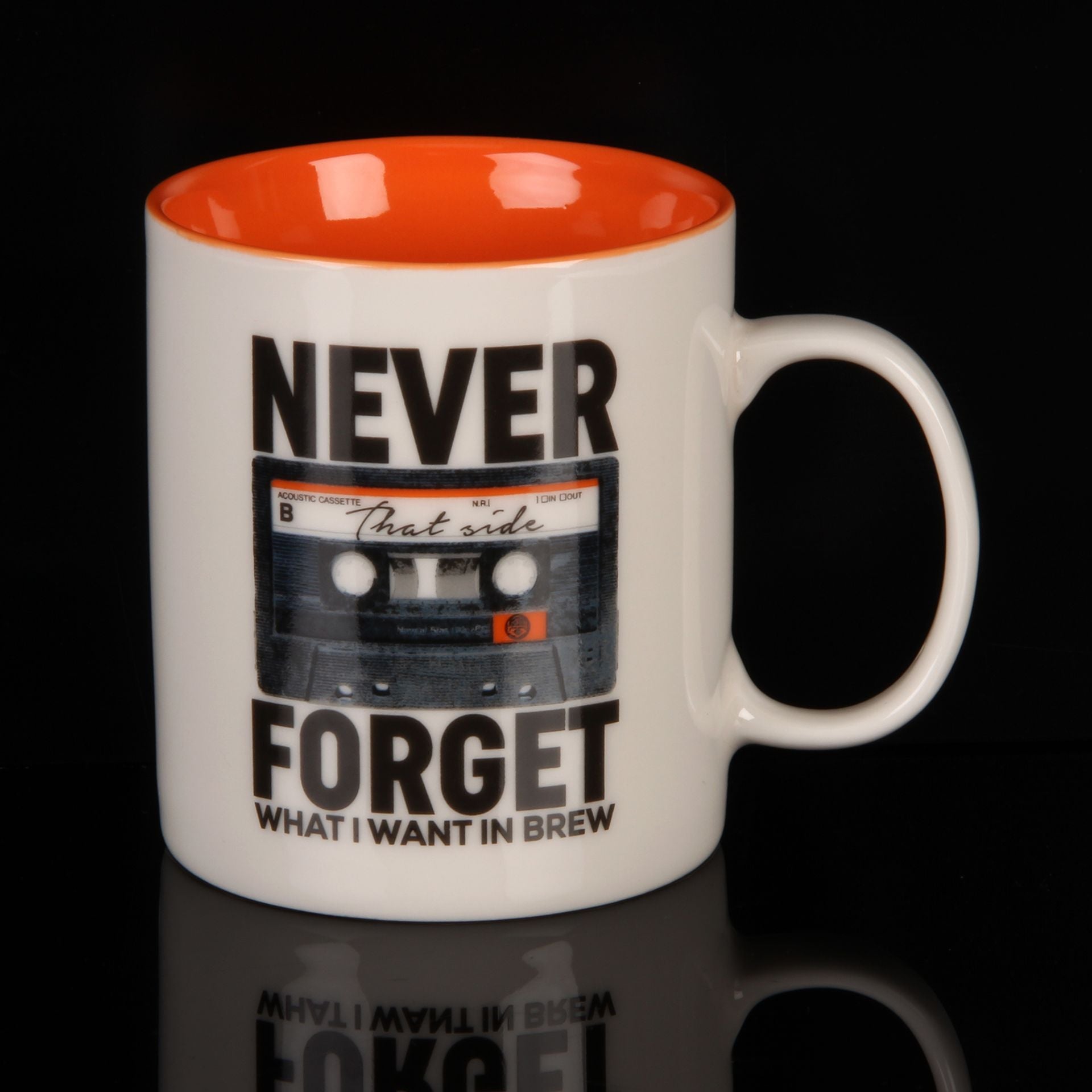 White mug with orange interior, black cassette tape design, and text on a black background