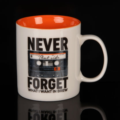 White mug with orange interior, black cassette tape design, and text on a black background