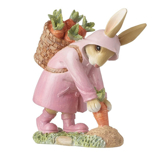 Figurine of a rabbit in a pink outfit holding carrots and a basket on a white background