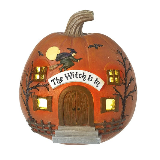 Pumpkin-shaped house with 'The Witch is In' sign and witch on a broomstick.