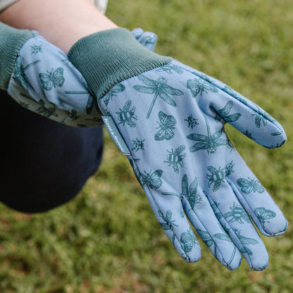 Gardening gloves with insect pattern held in front of a grass background
