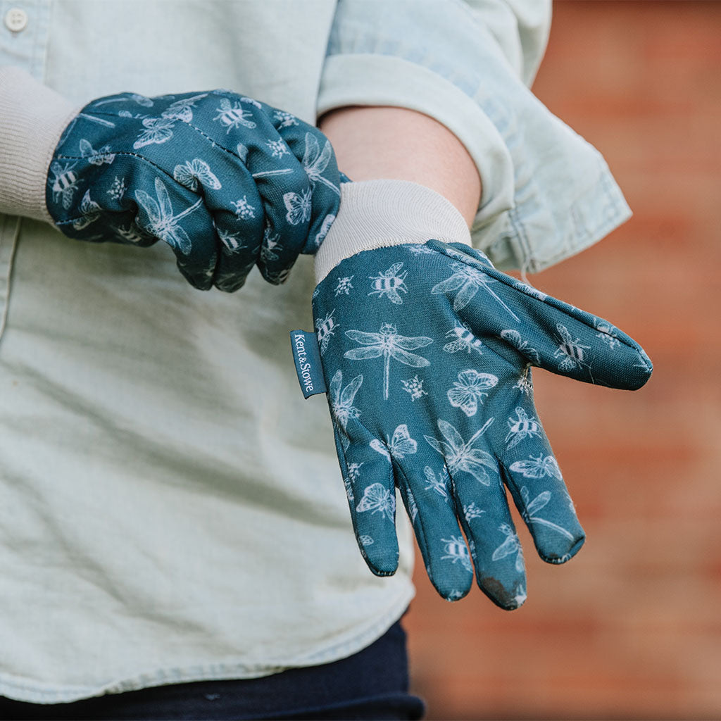 Person wearing blue gardening gloves with white patterns on a blurred background