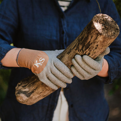 Person holding a log with gardening gloves on, wearing a blue jacket.