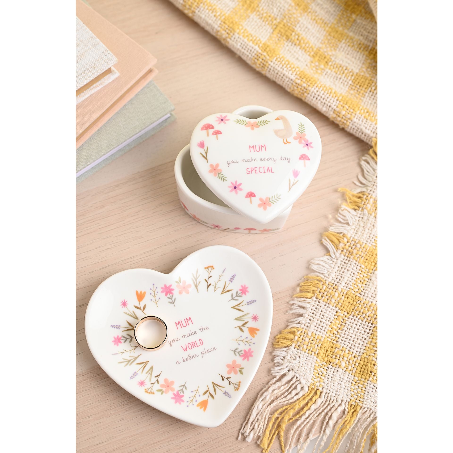 Heart-shaped ceramic trinket dishes with floral designs and text on a wooden surface.
