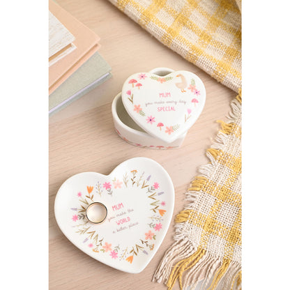 Heart-shaped ceramic trinket dishes with floral designs and text on a wooden surface.